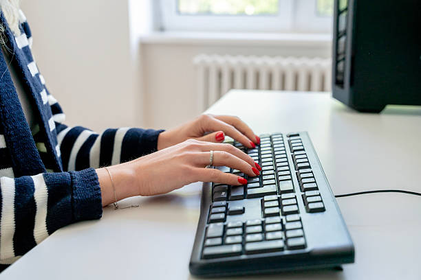 istock Typing on a keyboard at a modern workspace during the daytime with natural light streaming through large windows 2222119754