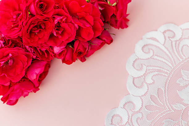 Cluster of deep pink roses paired with elegant white lace detail on a soft blush background, ideal for romantic or vintage themes.