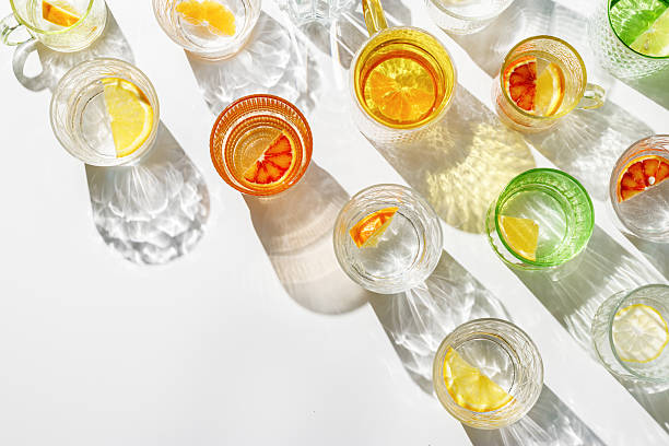 istock Vivid Glasses with cold detox water as summer still life pattern, shadow and sunlight reflection, closeup glass cups of infused fruit water, slises of lemon, orange, tangerine, healthy summer drink 2222124129