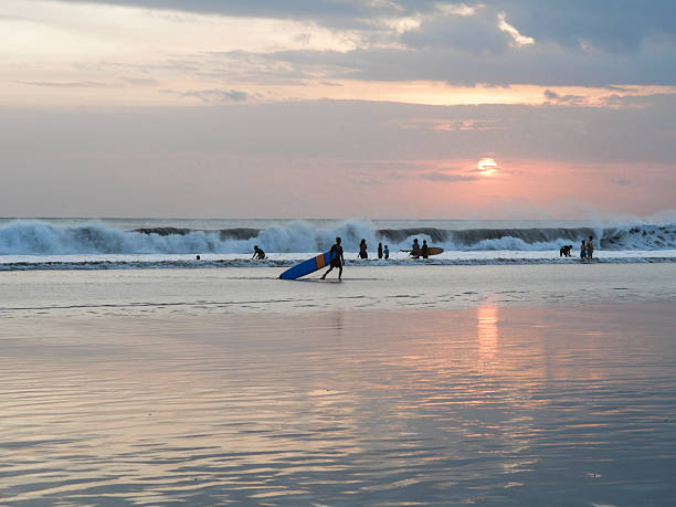istock Surfers at Sunset on a Serene Beach With Crashing Waves 2222127175