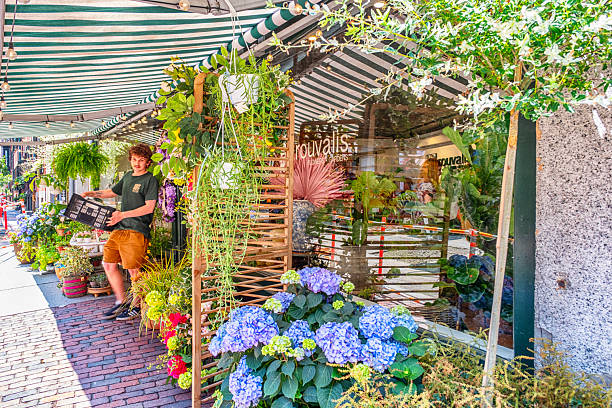 Rouvalis Flowers & Gardens in Boston and Winchester, MA offers boutique shopping, flower and plant delivery, garden services, and weddings. Boston is the capital and most populous city in the Commonwealth of Massachusetts in the United States. Young worker of the shop working.