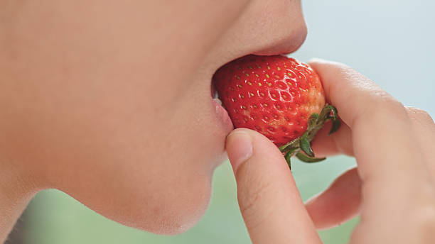 Close-up of mouth eating strawberry.