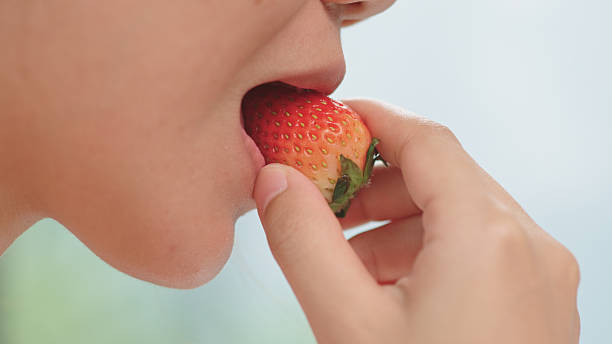 Close-up of mouth eating strawberry.