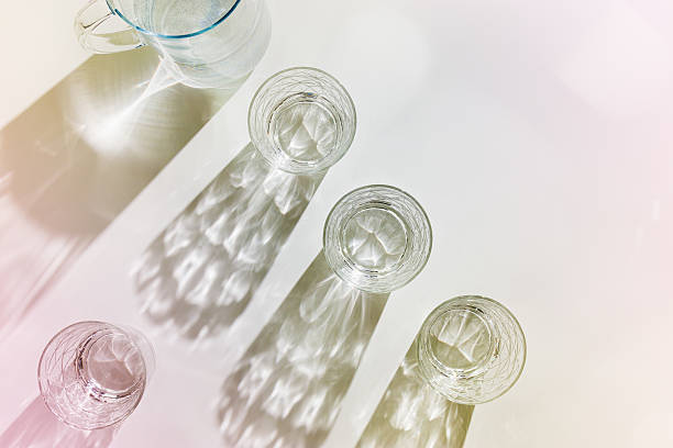 istock Water Glasses and water jug with Shadows and sunlight Reflection on white background, colored photo minimal style, aesthetic summer still life, refraction throug crystal shine cups, caustics 2222141172