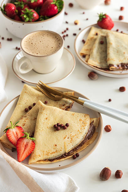 istock Crepes with chocolate hazelnut spread, strawberries and hazelnuts on a white wooden table. 2222141977