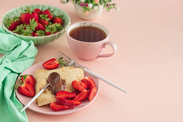 istock Crepes with chocolate spread and fresh strawberries, served with tea on pink background 2222142015