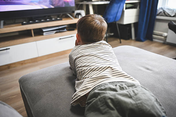 istock little boy is lying on the sofa and watching TV 2222146489