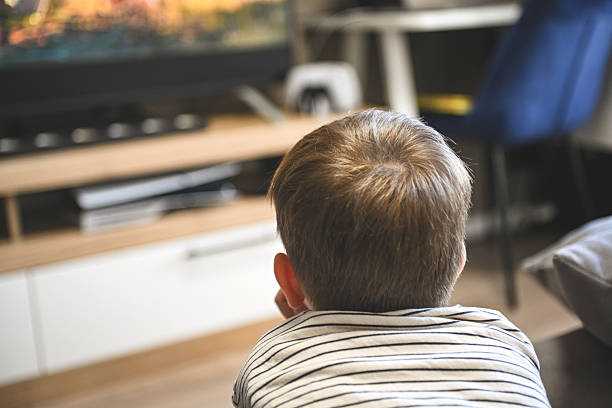 istock little boy is lying on the sofa and watching TV 2222150061