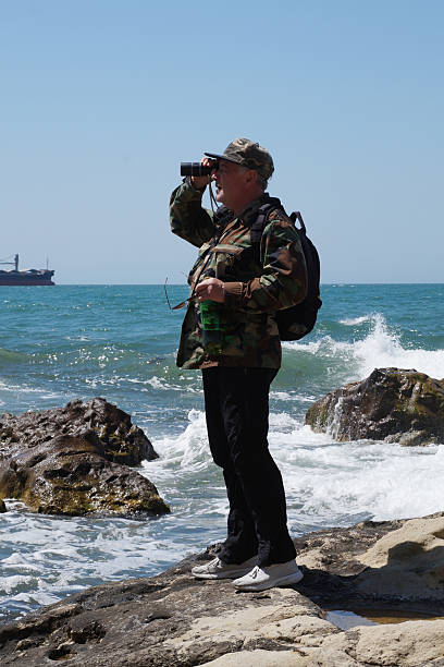 istock A man with a backpack looks through binoculars at the sea horizon 2222151216