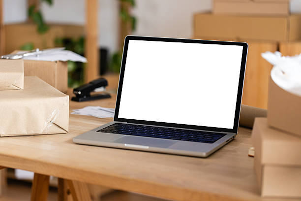 istock Laptop with blank screen on desk with parcels ready for shipping 2222151286