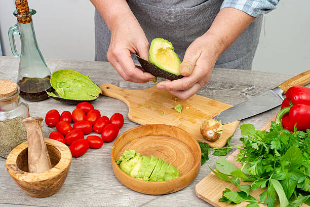 istock woman's hands preparing avocado to serve. Kitchen table with vegetables and spices 2222155002