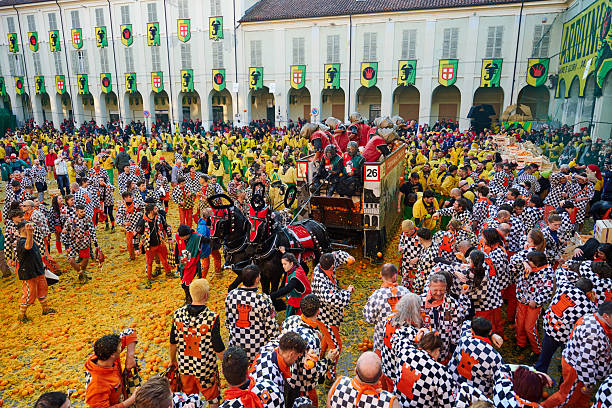 Ivrea, Italy - March 02, 2025: groups in traditional dressing take part in the Battle of the Oranges, where a teams of orange handlers on foot throw oranges (representing old weapons and stones) against aranceri of the team \