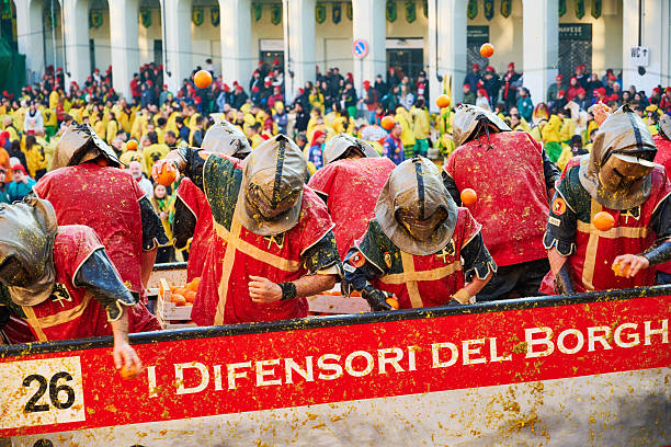 Ivrea, Italy - March 02, 2025: groups in traditional dressing take part in the Battle of the Oranges, where a teams of orange handlers on foot throw oranges (representing old weapons and stones) against aranceri of the team \