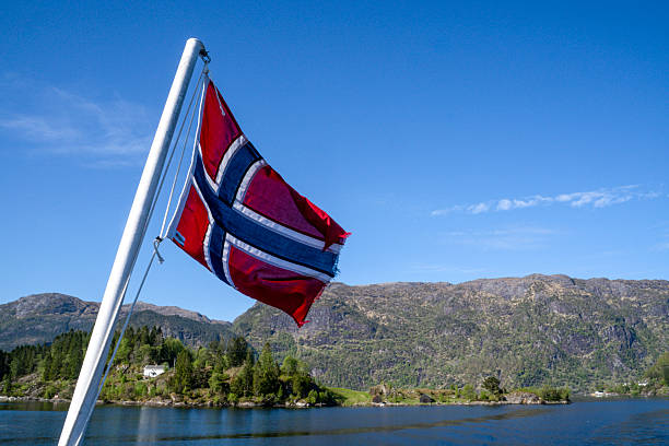 View past Norwegian flag to sea and islands