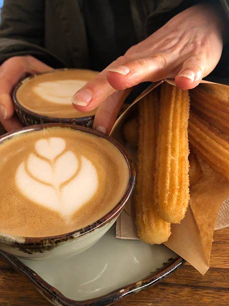 Woman's hands holding cappuccino and churros