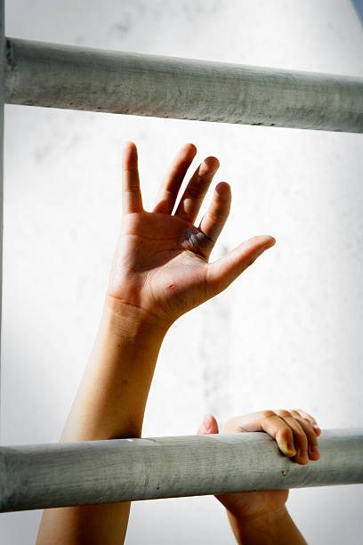 istock Hands Reaching for Freedom Through Metal Bars in Soft Light 2222170956