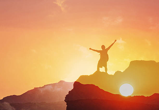 istock Positive man celebrating on mountain top, with arms raised up 2222172270