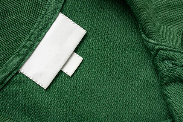 istock Blank white laundry care clothes label on green shirt fabric texture background 2222174571