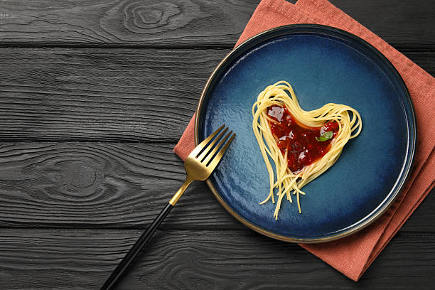 istock Heart made with spaghetti and sauce on black wooden table, top view. Space for text 2222182857