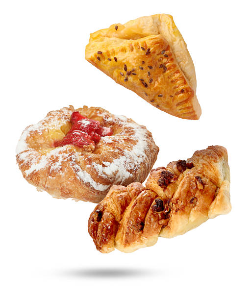 Different tasty puff pastries falling on white background