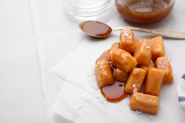 istock Yummy caramel candies and sea salt on white table. Space for text 2222183230