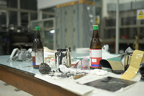 A cluttered printmaking workstation with turpentine bottles, ink, brushes, and cleaning materials. Cleaning the plate before applying turpentine ink