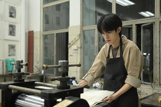 istock A young printmaker carefully places a printing blanket over an etching plate in a workshop. The etching press machine ensures a precise transfer of ink, creating a detailed print 2222188151