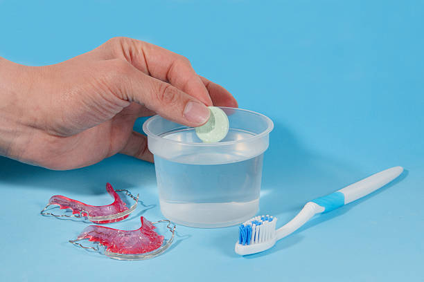 Doctor is preparing cleaning solution for retainer with effervescent tablet and toothbrush