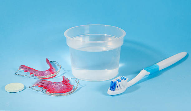 istock Orthodontic retainers soaking in disinfecting solution with toothbrush and effervescent tablet 2222192060