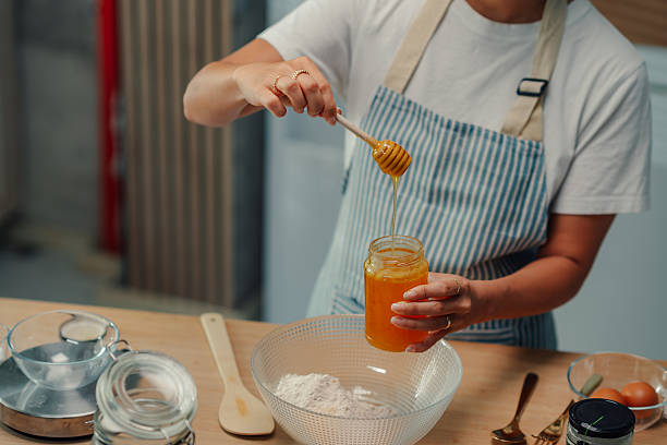 Baker pouring honey into jar in kitchen