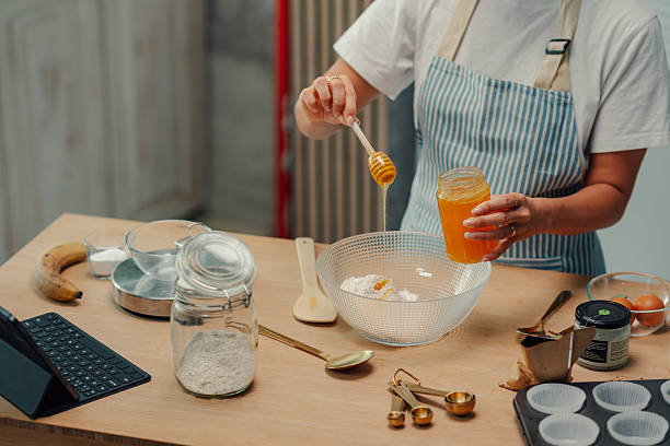 Pastry chef pouring honey into mixing bowl for baking banana bread