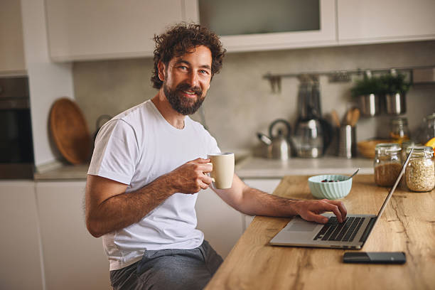 istock Smiling man working from home and drinking coffee in his kitchen 2222199018