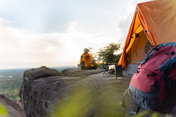 istock A person is sitting on a rock with a backpack next to them. The backpack is red and black 2222199882