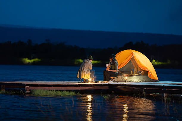istock Two people sitting on a dock by a lake 2222199999