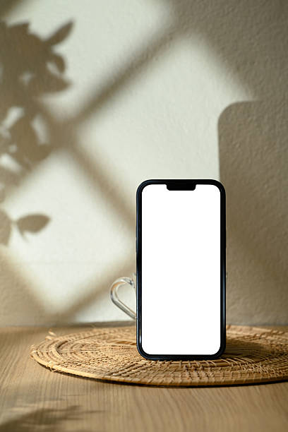 istock Smartphone with blank screen standing on rattan coaster with natural light and soft shadows 2222200431