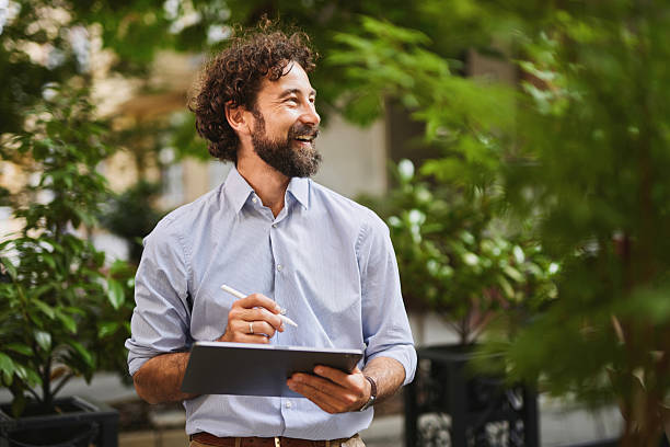 istock Smiling businessman working with tablet and stylus outdoors 2222200942