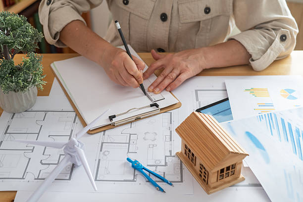 istock Architect is drawing the blueprints for a sustainable and ecological house powered by a wind turbine, showcasing the concept of renewable energy and green building design 2222204511
