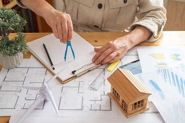 istock Environmental engineer uses a compass to draw plans for a sustainable house powered by a wind turbine, focusing on ecological innovation for the future 2222204512