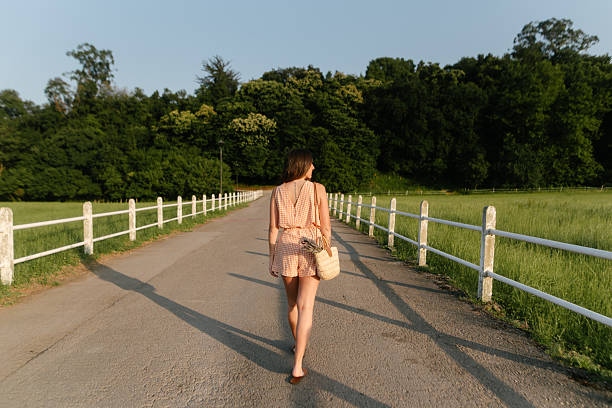 Rear view of a young woman walking on a rural road