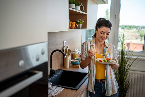istock Smiling woman enjoying fresh salad in modern kitchen 2222210845