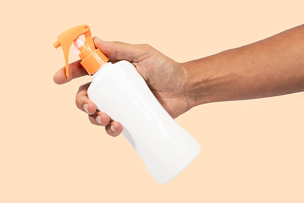 istock Male hand holding sunscreen cream spray isolated on light orange background 2222211187