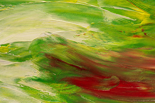 Palette knives resting on an artist's palette with oil paints and a blurred painting in the background