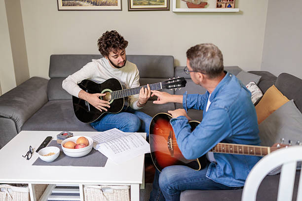 istock Man and boy reading sheet music while playing guitar 2222215588