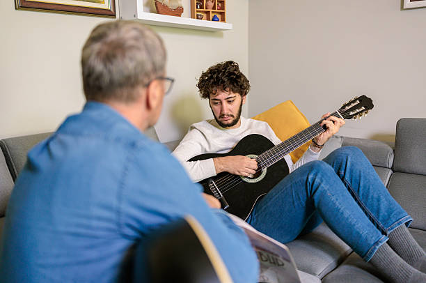 istock Boy learning guitar as father points to notes in a music book 2222217127