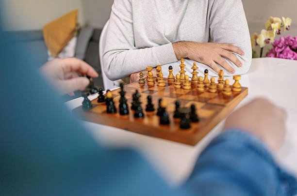 On Father's Day, a dad and his son sit at the table playing chess. They seem happy and focused on the moves.