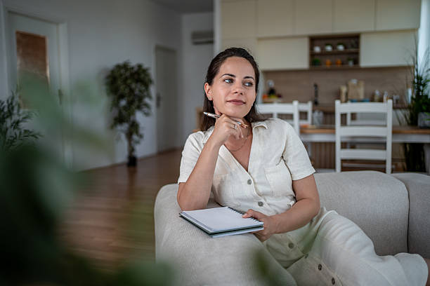 istock Woman relaxing on sofa and thinking with notebook and pen 2222220401
