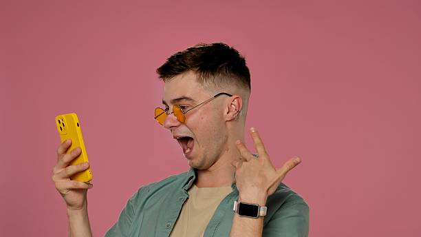istock Excited Young Man with Smartphone on Pink Background 2222222425