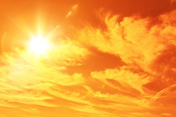 Dramatic heat wave sky with swirling orange and yellow clouds and blazing sun on the sky stock photo