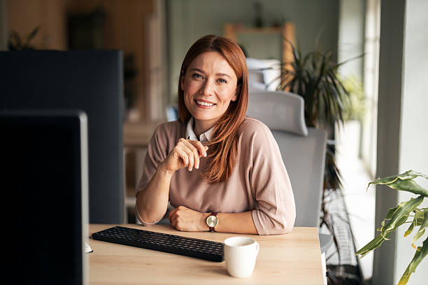 istock Woman Smiling at Desk in Bright Office Workspace 2222228133