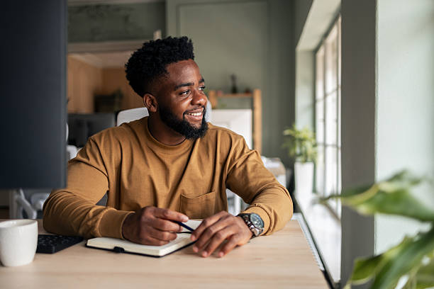 istock Smiling Man Taking Notes Seated at a Well-Lit Office Desk 2222228206